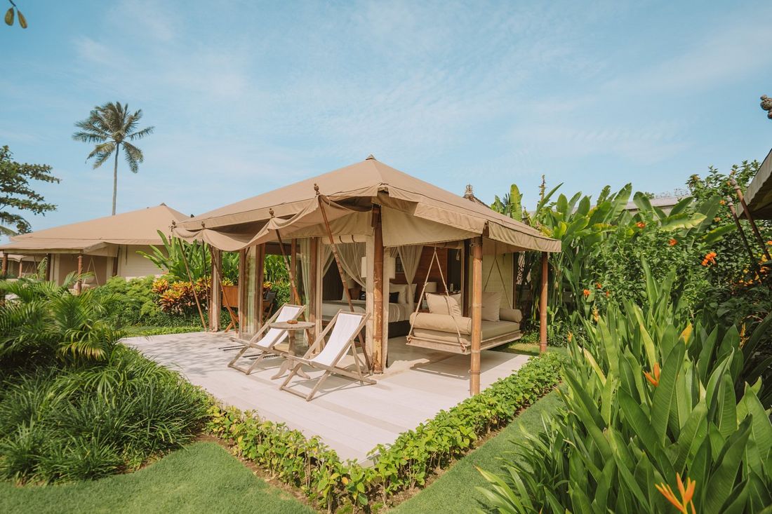 A glamping tent with a swing daybed and loungers